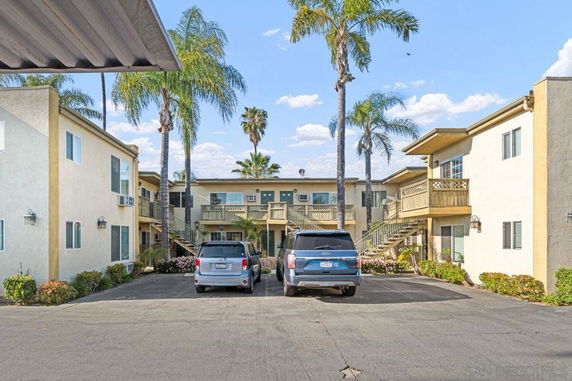 Outdoor parking area in front of a two-story apartment complex.