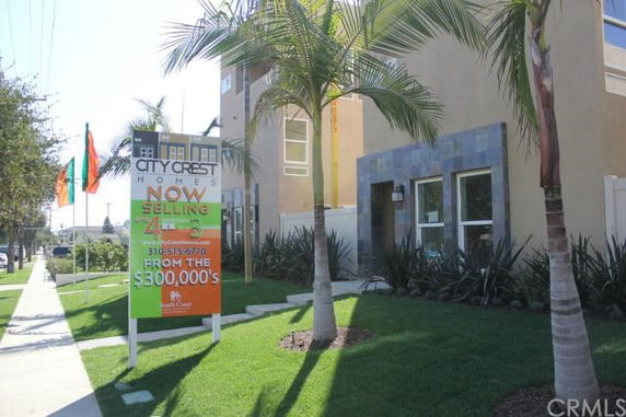 Front view of a multi-story residential building with sales sign.