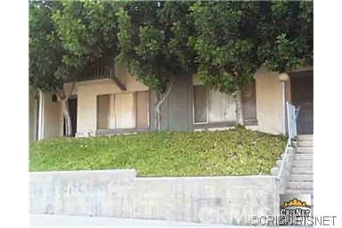 Front view of a multi-story building with stairs and trees.