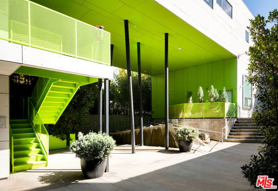 Elevated view of a modern building with green exterior and metal stairs.