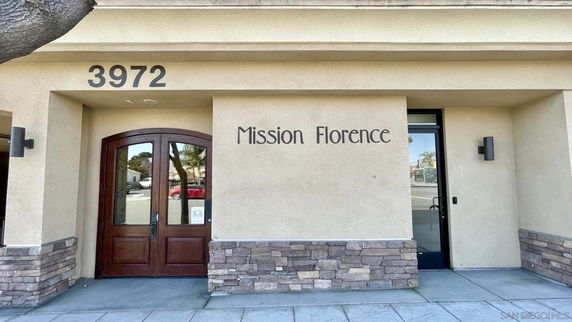 Front view of a building with stone accents and wooden double doors, labeled Mission Florence.