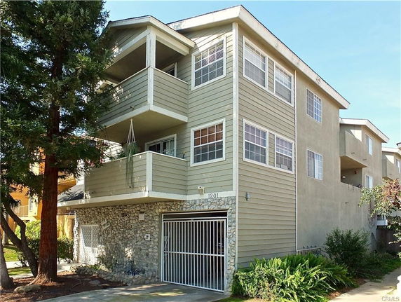 Front view of a multi-story house with a gated garage and balconies.