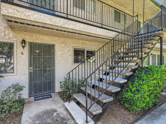 Front view of a two-story apartment building with an external staircase leading to the second floor.