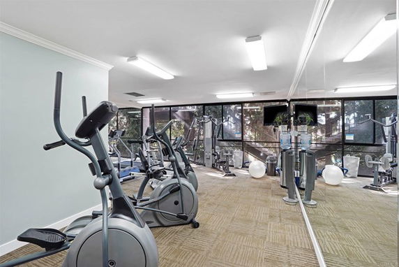 Interior of a gym with exercise equipment and large mirrors on one wall.