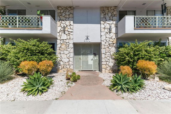 Front view of a building entrance with stone accents and balconies.