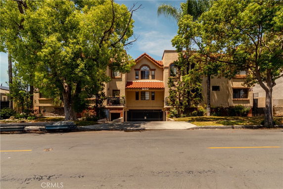 Front view of a two-story residential building with a tiled roof and an arched window.