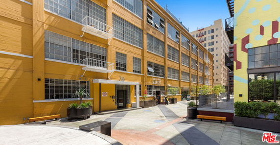 Front view of a yellow multi-story building with large windows.