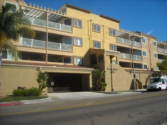 Front view of a multi-story apartment building with balconies and beige exterior.