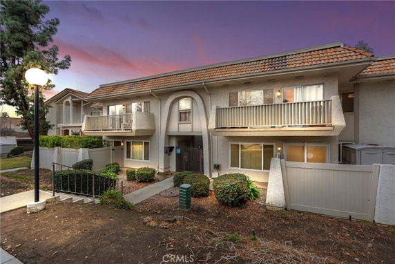 Front view of a two-story residential building with balconies and a tiled roof.