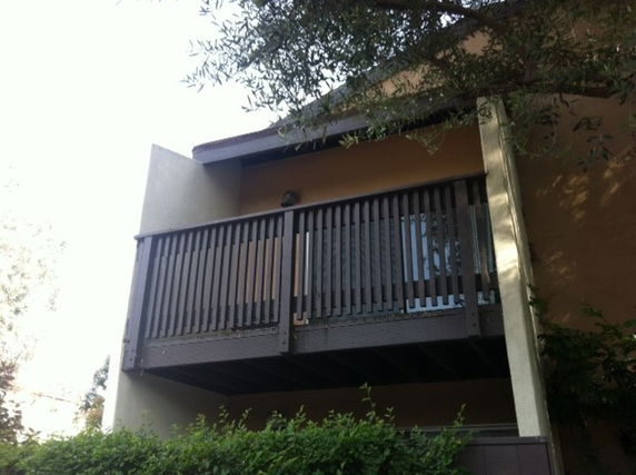 View of a building with a wooden balcony and sloped roof.