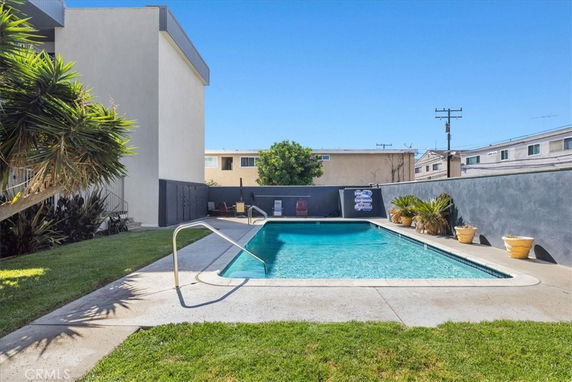 Outdoor swimming pool next to a building with a surrounding fence.