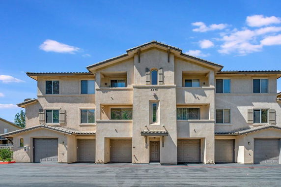 Front view of a multi-story residential building with garages on the ground floor.