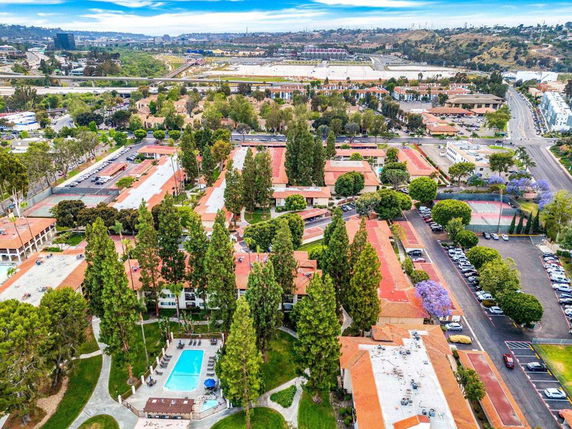 Wide angle view of a residential complex with multiple buildings, a swimming pool, and trees.