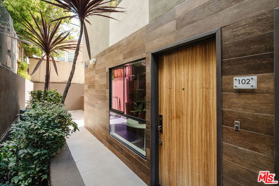 Front view of a modern home entrance with wood paneling and a small window.
