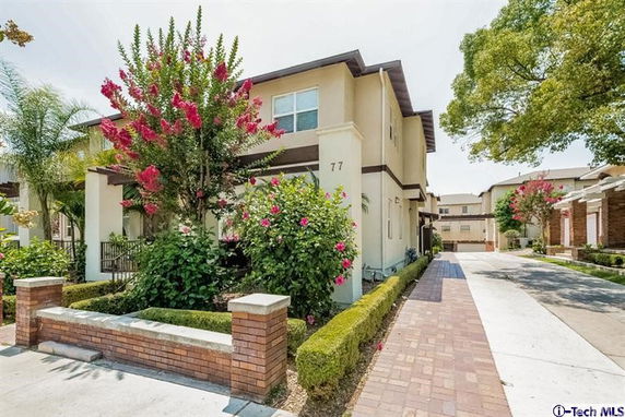 Front view of a two-story house with landscaped shrubs and a driveway.