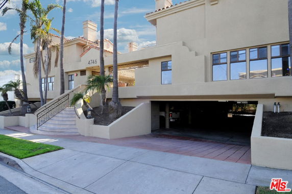 Front view of a house with an elevated entrance and a parking area below.