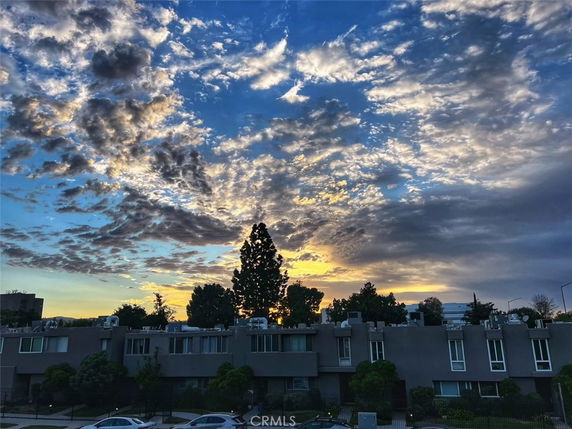 View of a residential building with a dramatic sky and clouds at sunset.