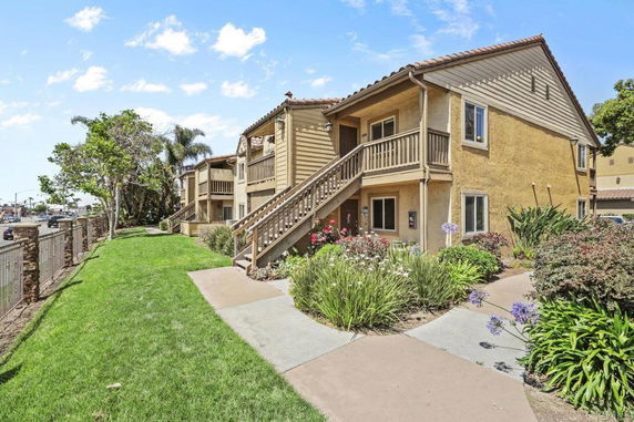 Front view of a two-story house with stairs and landscaped walkway.