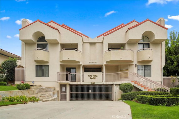 Front view of a multi-story residential building with balconies and a gated entrance.