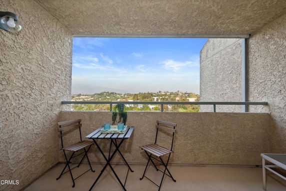 Balcony with a small table and chairs overlooking a scenic view.