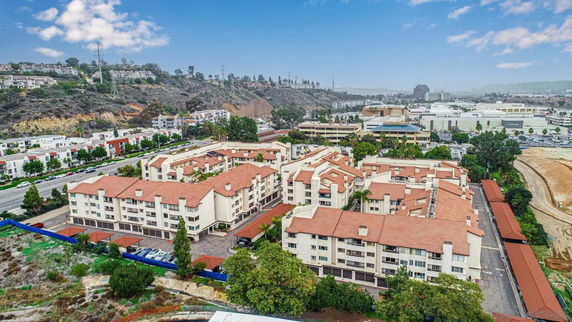 Panoramic view of a large apartment complex with red roofs in a hilly area.