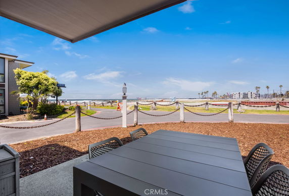 Coastal view from a patio with a modern outdoor dining table, overlooking a path near the beach.