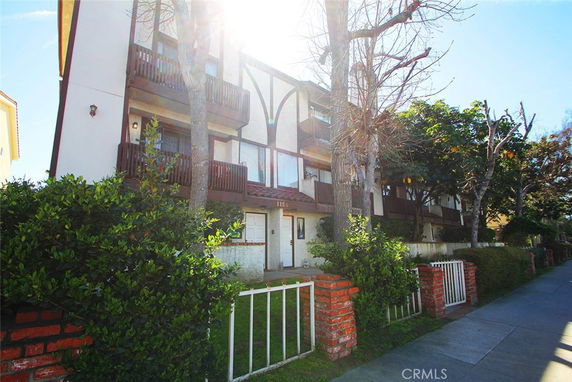 Front view of a multi-story building with balconies and bare trees.