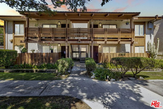 Front view of a two-story building with wooden balconies and fenced entrances.