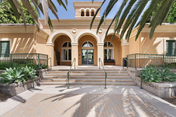 Front view of a building with arched entrances and steps leading up to the main doors.