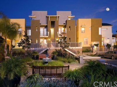 Front view of a modern multi-story building with multiple entrances and balconies at night.
