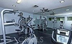 Indoor gym area with various exercise equipment and mirrors.