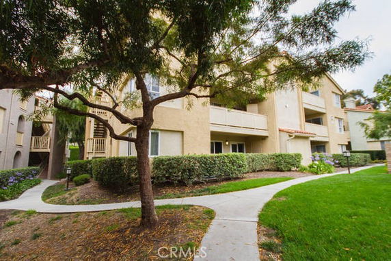 Front view of a multi-story apartment building with balconies and landscaped surroundings.
