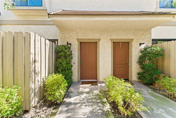 Front view of a building entrance with two doors and surrounding greenery.