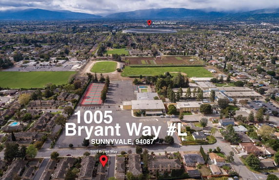 Aerial view of a residential area with a school, playgrounds, and distant mountainous landscape.