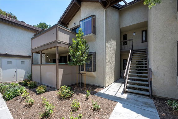 Front view of a two-story building with a staircase leading to the second floor and a small balcony.