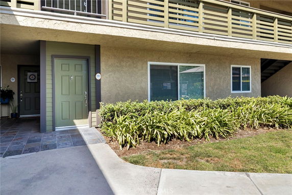 Front view of a building entrance with plants and a walkway.
