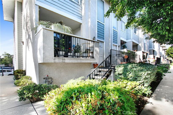 Front view of a multi-story residential building with balconies and plants.