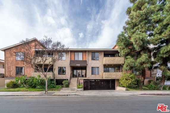 Front view of a multi-story residential building with balconies and garage entrance.
