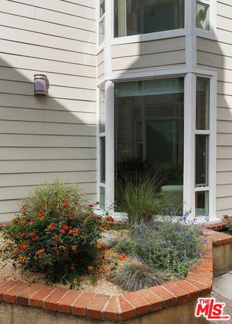 Front view of a house corner with large windows and garden bed
