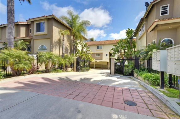 Front view of a multi-story residential building with gated entrance and mailboxes.
