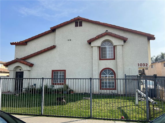 Front view of a two-story house with red-tiled roof and fenced yard.