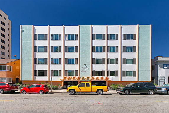 Front view of a multi-story residential building with cars parked in front.