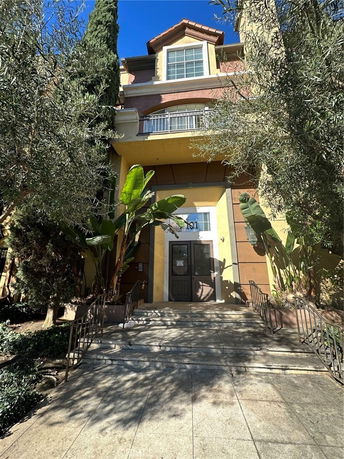 Front view of a multi-story building with an entrance and ornamental plants.