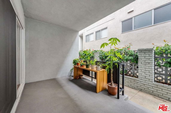 Outdoor area with potted plants, enclosed by a wall with decorative blocks.