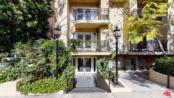 Front view of a building with balconies and greenery.