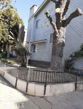 Front view of a two-story house with a chimney and a fenced front area.