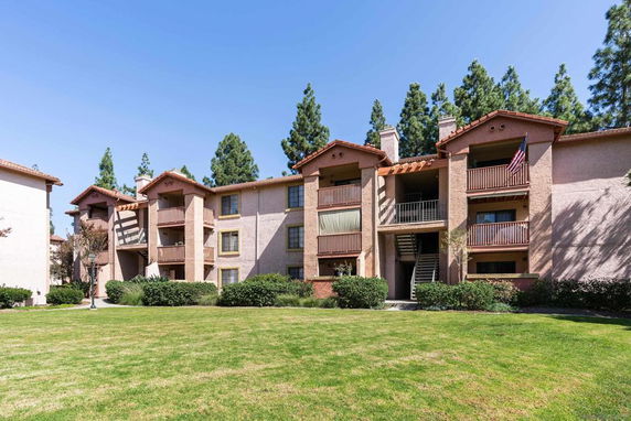 Front view of a multi-story apartment building with balconies and a staircase.