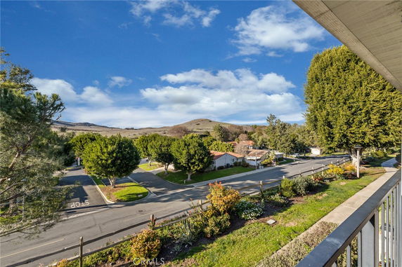 Panoramic view of a neighborhood street with trees and hills in the background.