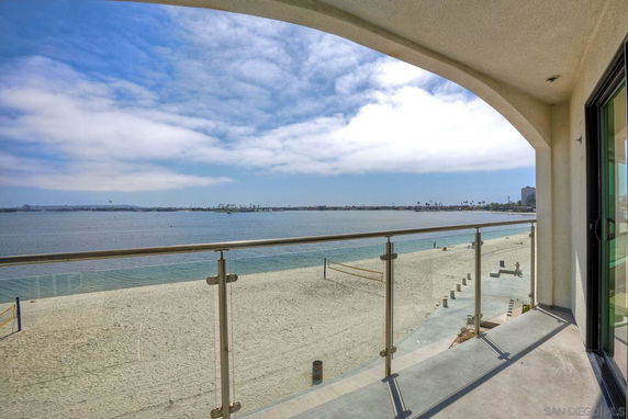 Panoramic view from a balcony showcasing a sandy beach and a body of water.
