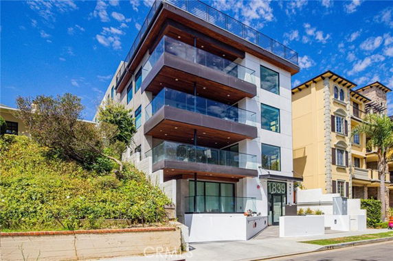 Front view of a modern multi-story building with large glass balconies.